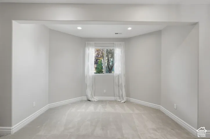 Recessed nook featuring neutral wall-to-wall carpeting, recessed ceiling lighting, and a window with exterior greenery
