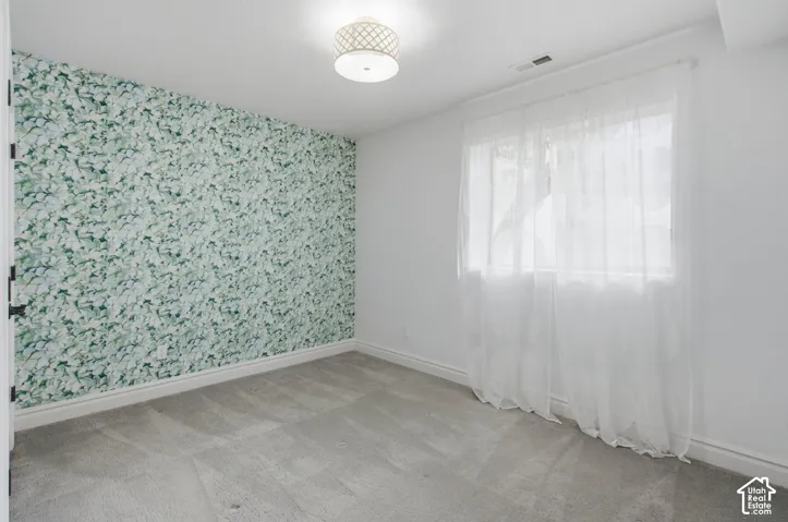 Room featuring a floral accent wall, neutral carpeting, and a drum-style ceiling light fixture