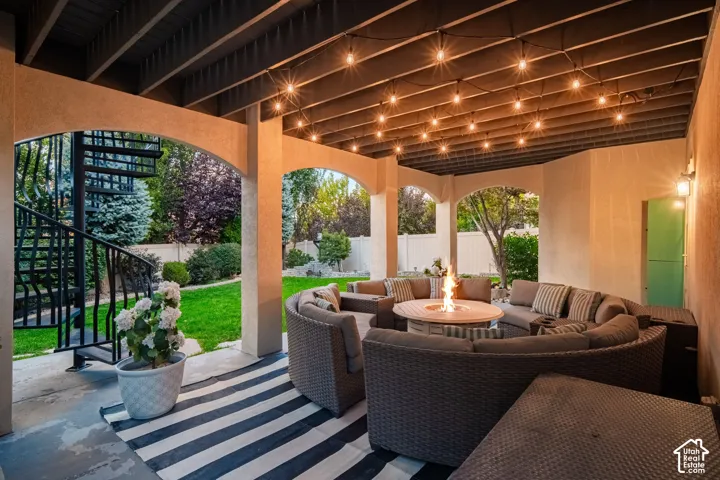 Covered patio featuring an arched entryway, string lighting, and a spiral staircase with metal railings