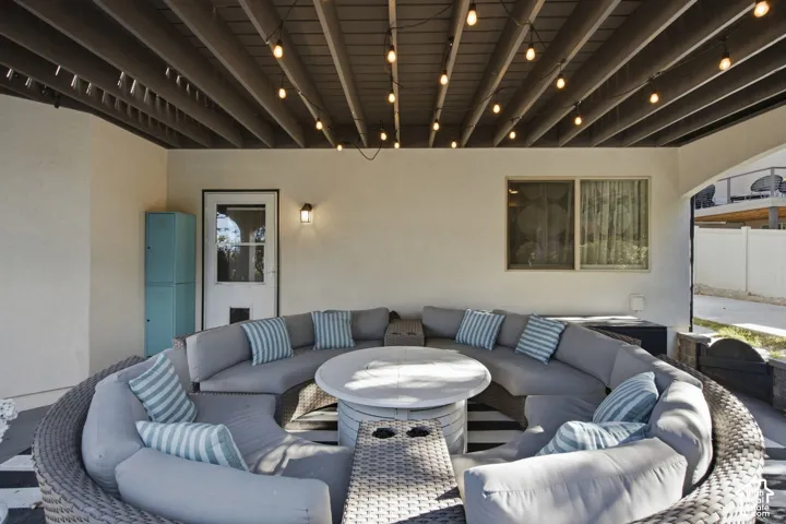 Covered patio featuring an exposed-beam ceiling and wall-mounted exterior lighting
