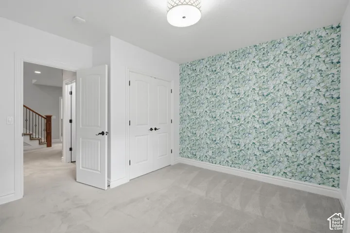 Bedroom featuring patterned floral wallpaper, carpeted flooring, a double-door closet, and a drum-style ceiling light fixture