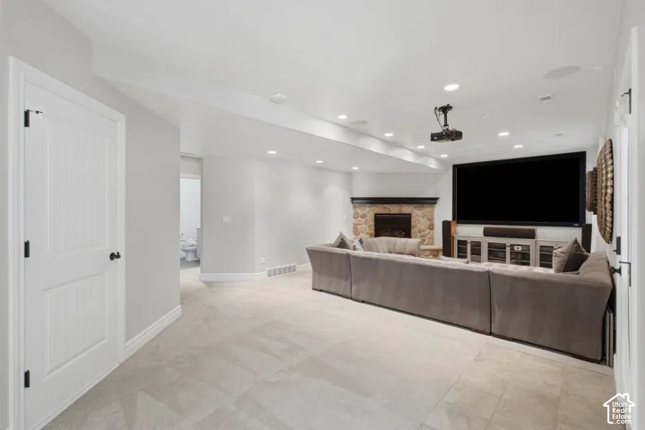 Neutral-toned carpeted flooring, recessed lighting, corner stone fireplace with a wood mantel, and built-in projector system