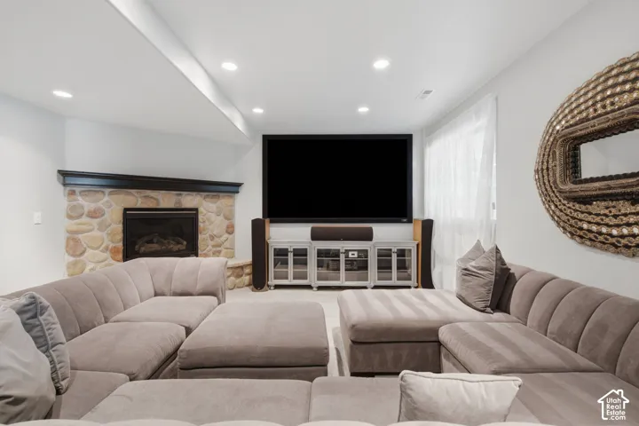 Corner fireplace featuring natural stone masonry and a dark wood mantel, complemented by recessed ceiling lighting