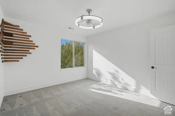 Room featuring a custom tiered wood wall installation, neutral carpeting, a dual-tone circular LED ceiling fan, and a two-panel interior door