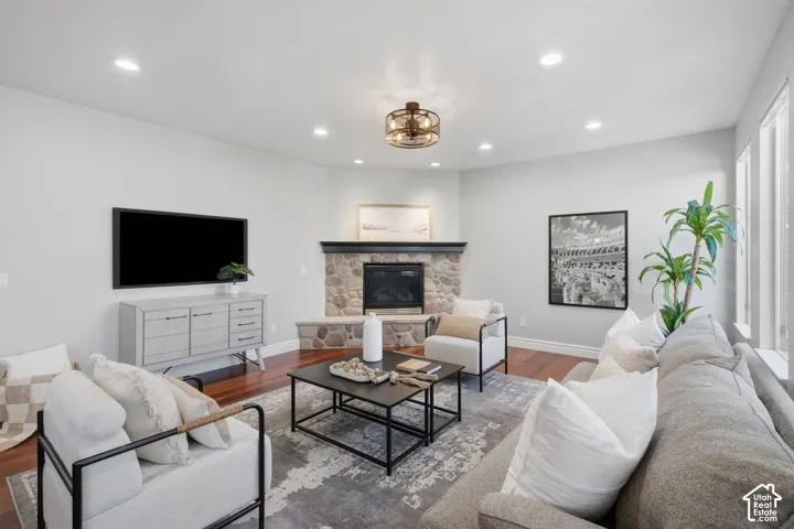 Living area featuring wood-finish flooring, recessed lighting, and a corner stone-surround fireplace with a hearth and mantle