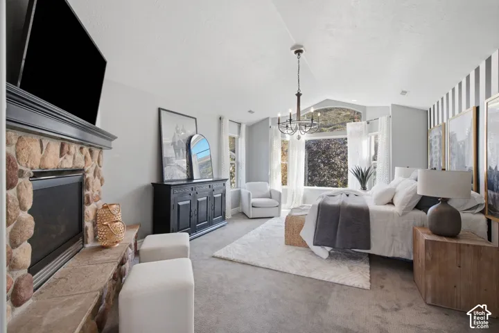 Vaulted ceilings with a prominent floor-to-ceiling stone fireplace, arched window, and chandelier lighting