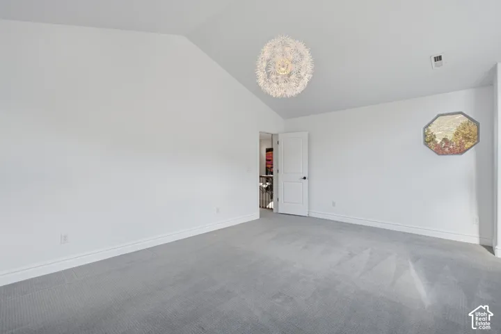 Vaulted ceiling, spherical multi-filament chandelier, octagonal window, and wall-to-wall carpeting