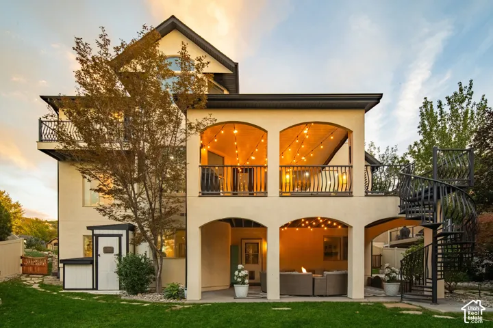 Multi-level exterior with stucco finish, arched openings, and black wrought iron railings