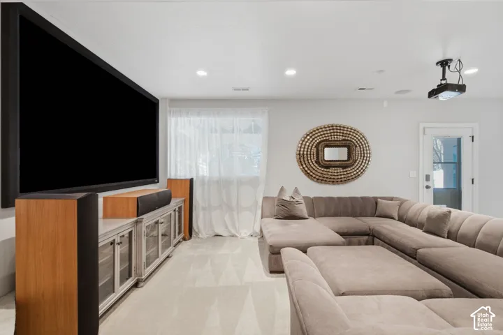 Media room featuring a wall-mounted projection screen, ceiling-mounted projector, recessed lighting, and carpeting