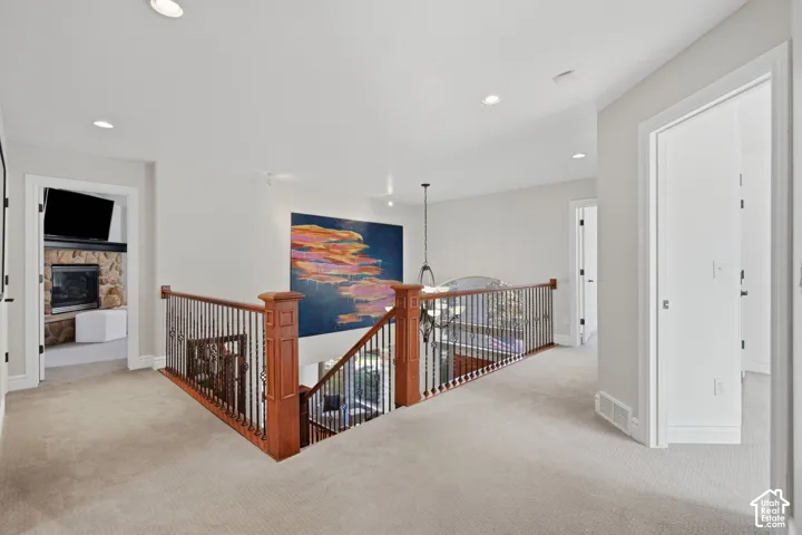 Landing area featuring neutral carpeting, recessed lighting, and a staircase with a wood railing and metal balusters
