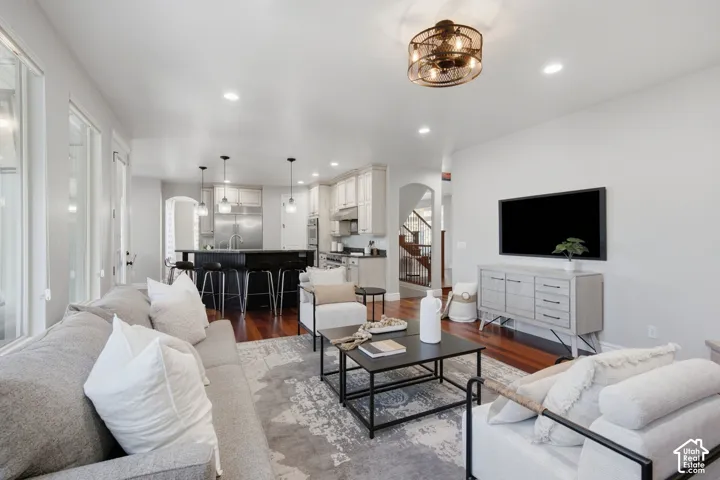 Open-concept living space featuring wood-finish flooring, recessed lighting, and a kitchen equipped with a dark-toned center island, stainless steel appliances, and light-colored cabinetry