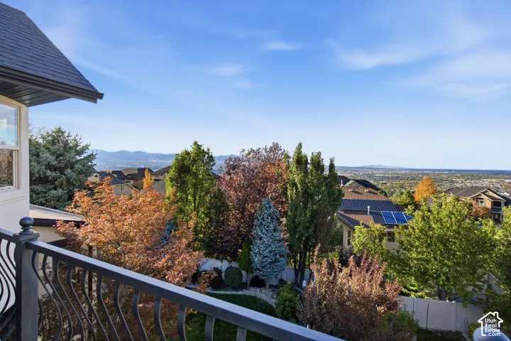 Elevated deck featuring metal railing, mature trees, and expansive horizon landscape
