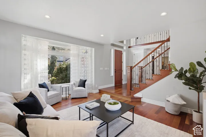 Wood-finish flooring, recessed lighting, large window bay, and wood staircase with decorative metal balusters