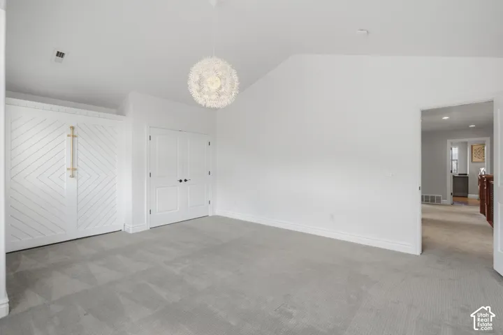 Vaulted ceilings, built-in cabinetry with geometric detailing, custom-style double doors, and a decorative globe pendant light fixture