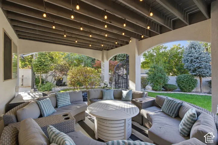Covered patio featuring an exposed-beam ceiling, arched architectural detailing, and a spiral staircase