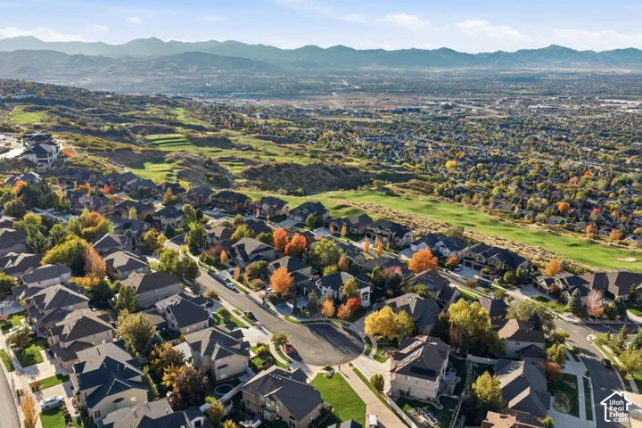 Aerial perspective of a hillside residential neighborhood featuring expansive mountain horizons, proximity to open green space, and mature trees throughout the landscape