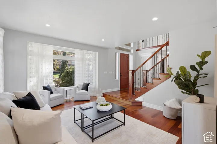 Living area featuring large windows, wood-finish flooring, recessed lighting, and a staircase with metal balusters and a wood handrail