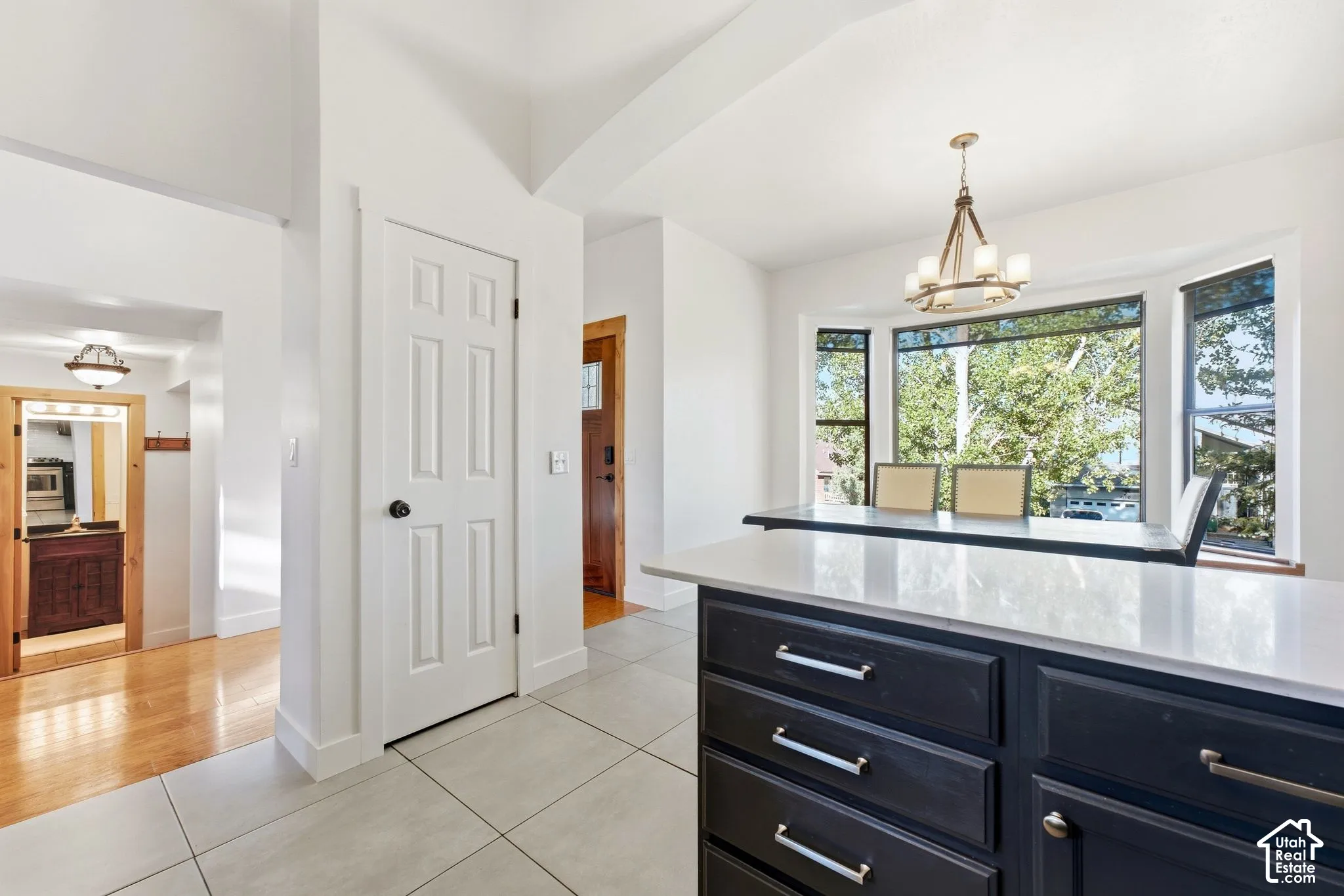 Kitchen island with a light-toned countertop, dark base cabinetry, and brushed nickel hardware