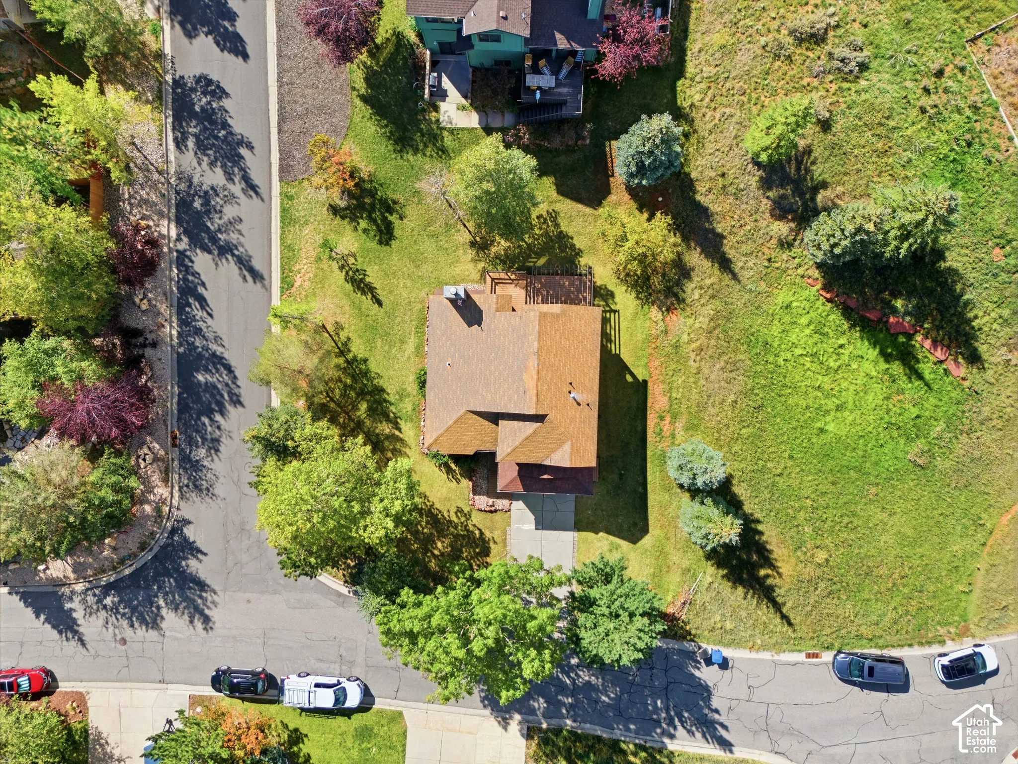 Property featuring a brown shingle roof, attached driveway, and a wooden deck