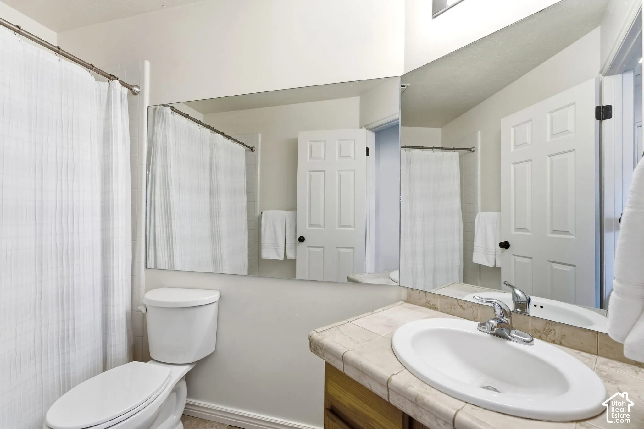 Vanity with an oval sink, chrome faucet, and tiled countertop