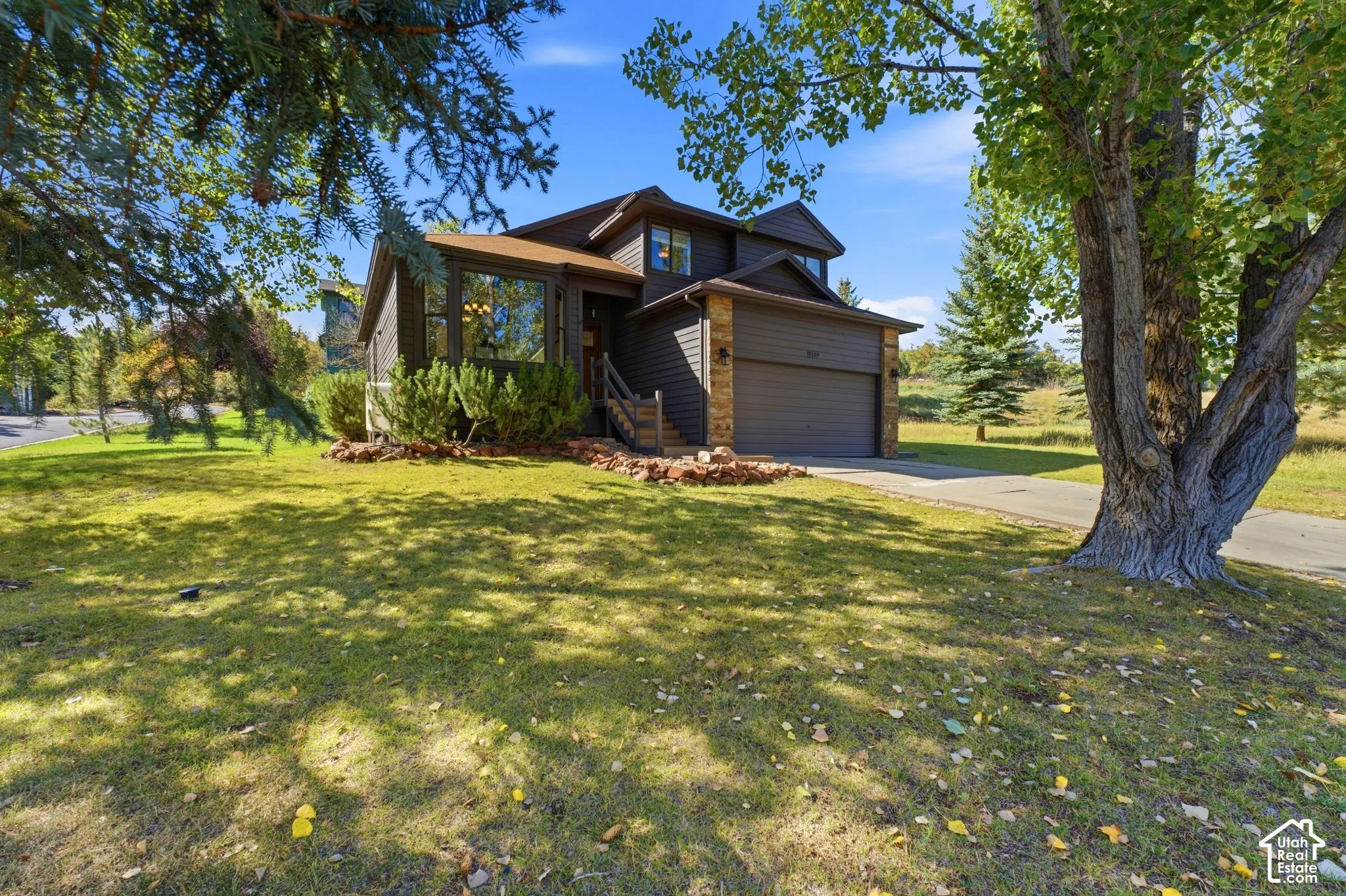 Brown siding exterior with stone accents, a two-car garage, and a prominent bay window