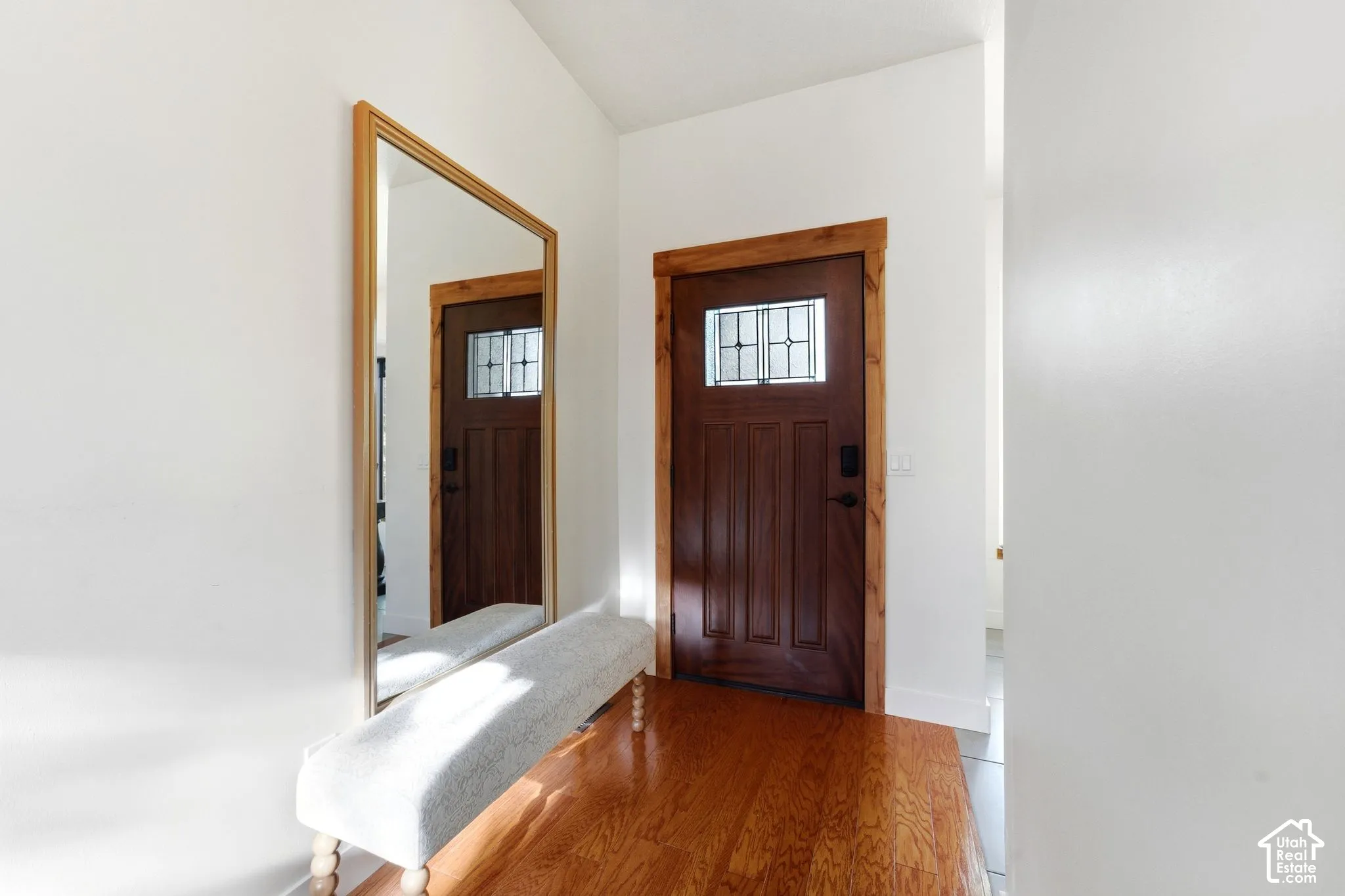 Rich wood-finish flooring and solid wood front door with decorative glass inserts