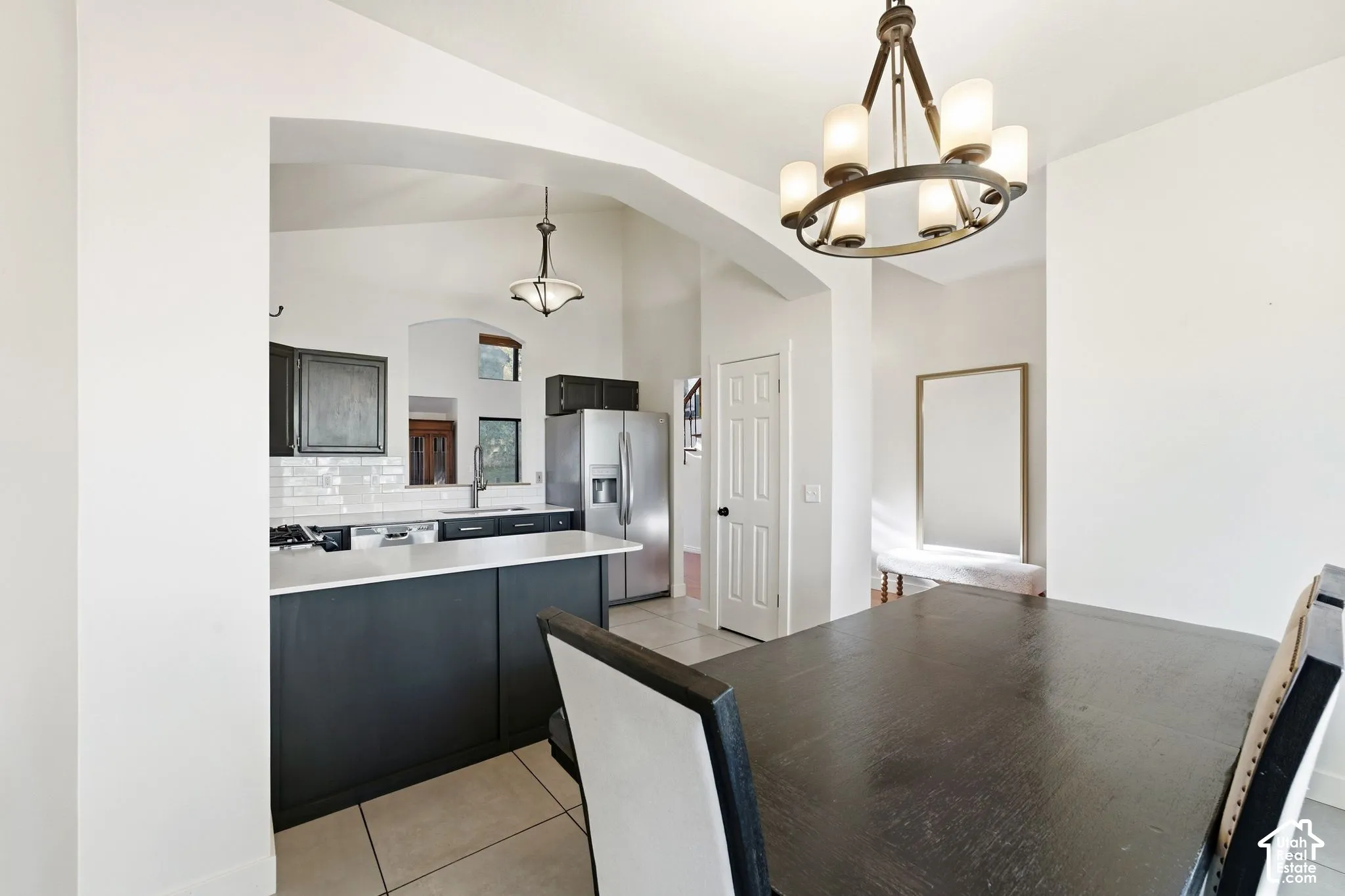 Open concept kitchen with white subway tile backsplash, dark cabinetry, and a large central island
