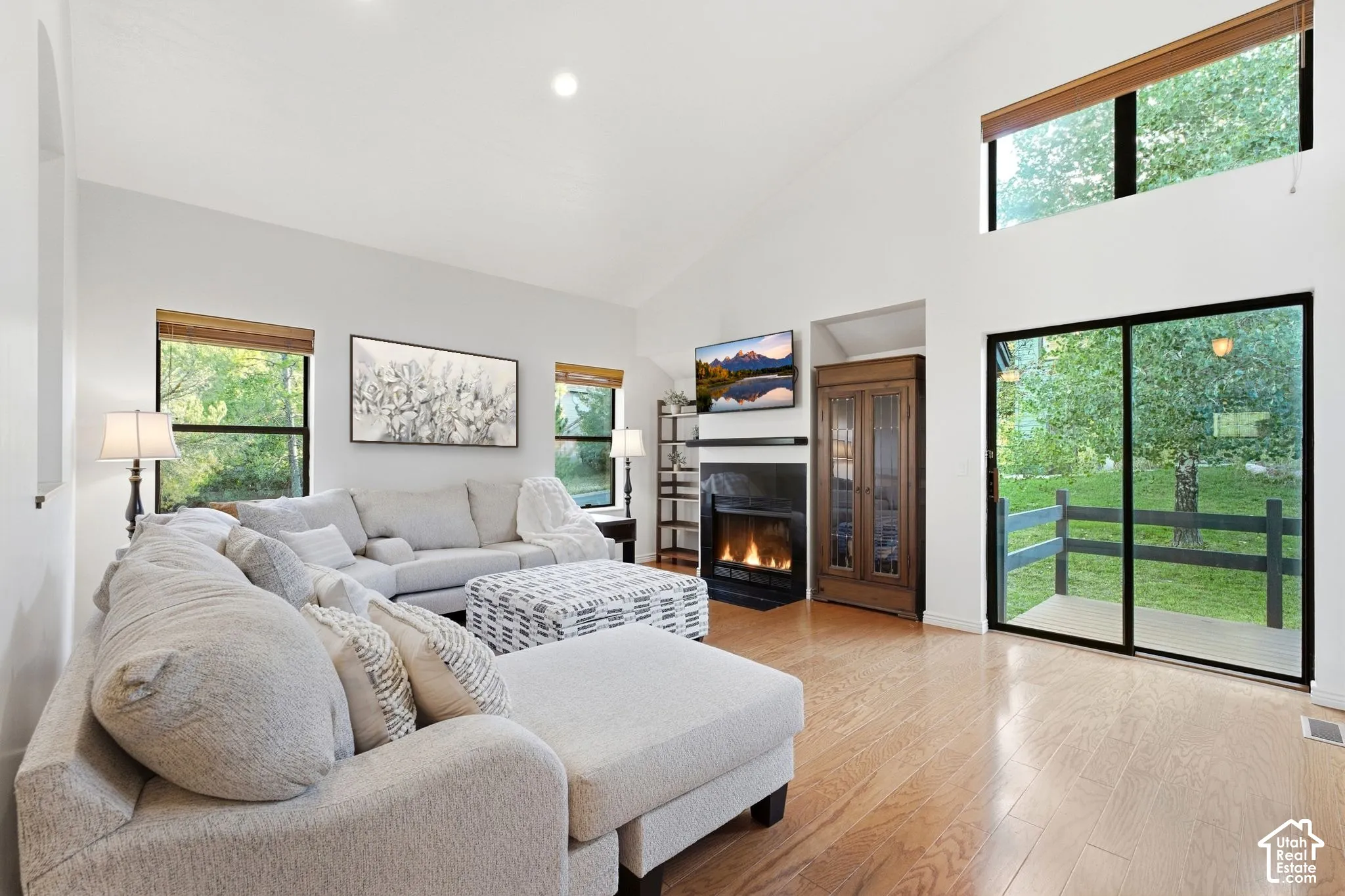 Vaulted ceiling with recessed lighting, wood-finish flooring, and a fireplace with a dark mantel