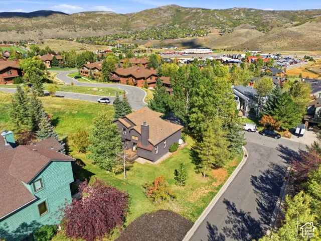 Mountainous backdrop, residential community, winding paved roads, mature trees, and varied architectural styles