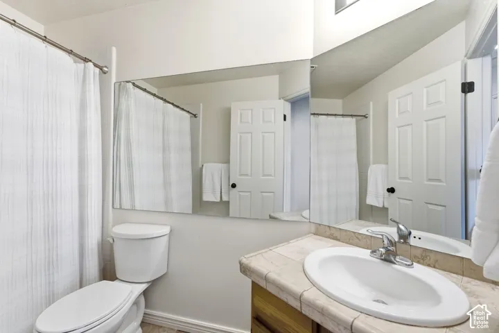 Vanity with an oval sink, chrome faucet, and tiled countertop