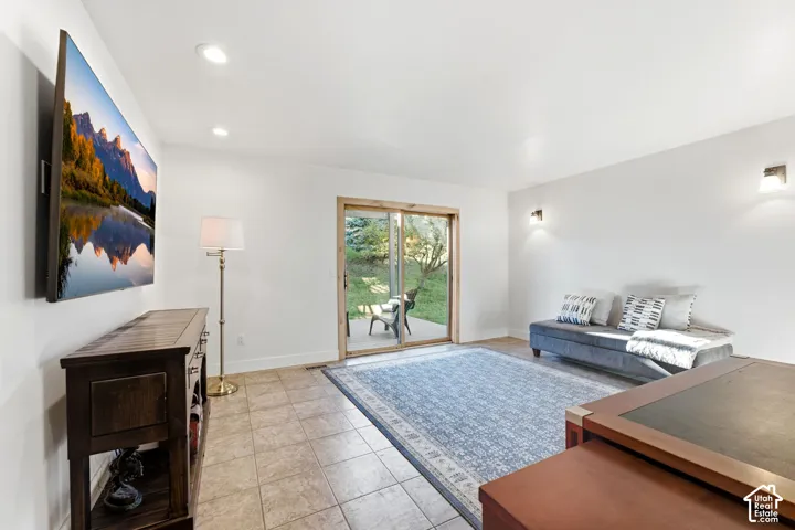 Recessed ceiling lighting, wall-mounted sconces, and a sliding glass door with wood trim