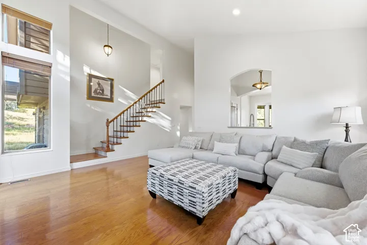 High ceilings with recessed lighting, wood-finish flooring, a wood staircase with iron balusters, an arched pass-through window, and large windows