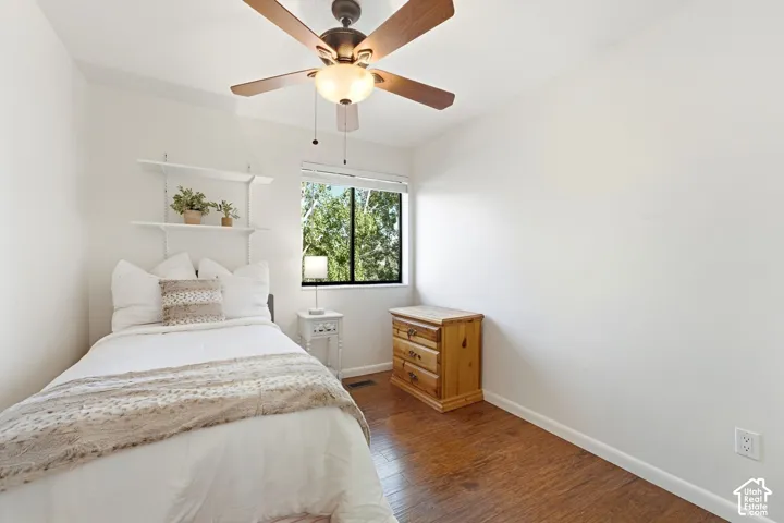 Hardwood-finish flooring, built-in shelving, ceiling fan with integrated lighting, and a single window with blinds