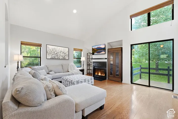 Vaulted ceiling with recessed lighting, wood-finish flooring, and a fireplace with a dark mantel