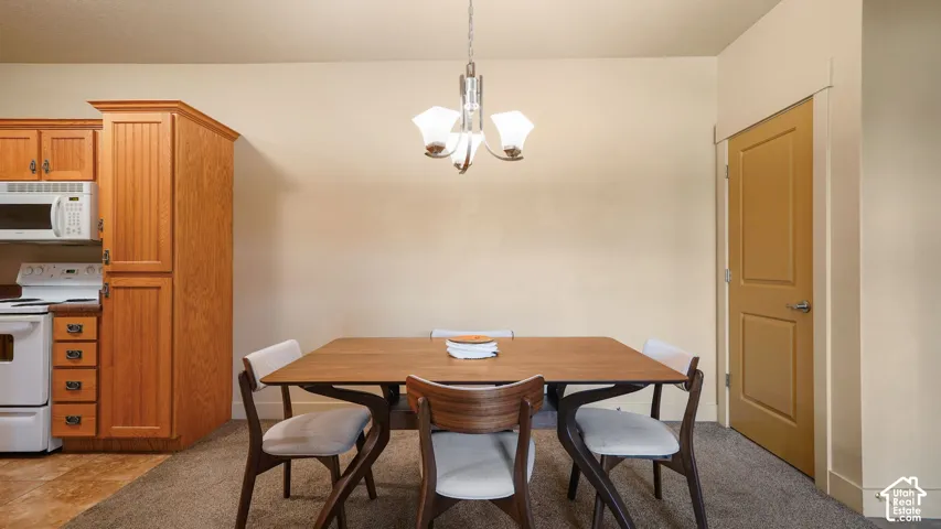Dining area featuring an overhead chandelier, a two-panel interior door with brushed nickel hardware, and wood-finish cabinetry