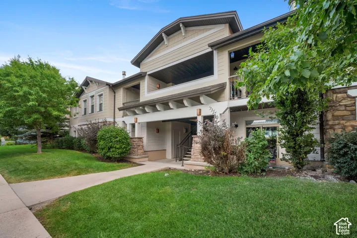 Multi-story exterior with a stone and siding facade, featuring a covered entry, upper-level balcony, and surrounding landscaping