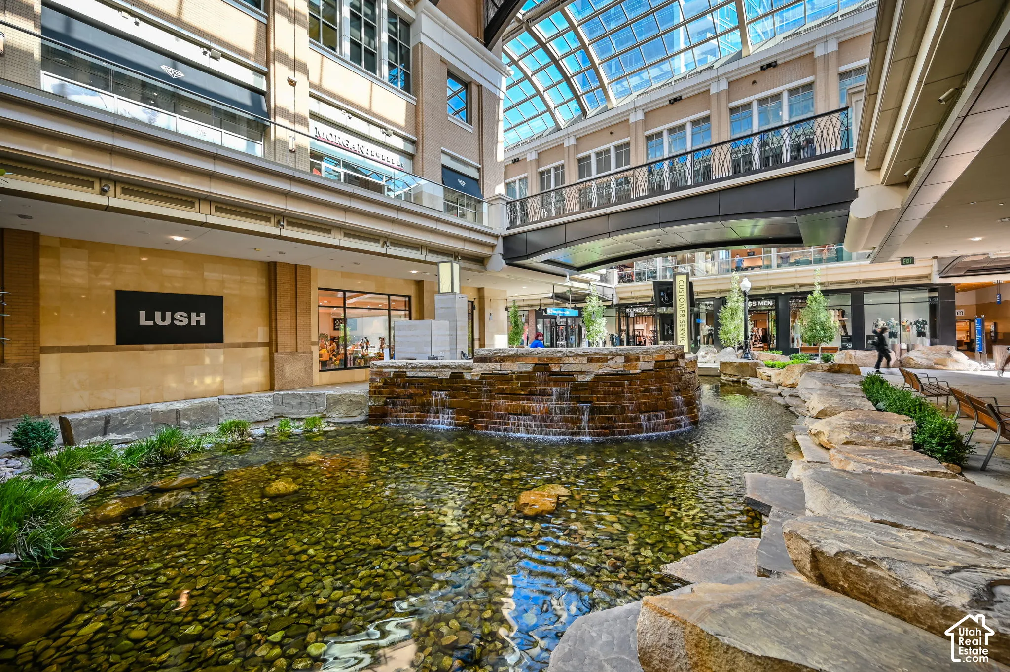 Water feature with stone retaining walls, rock-lined basin, and a tiered waterfall element