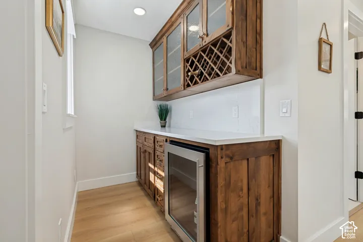 Wood-finish flooring, built-in cabinetry, quartz countertops, integrated beverage cooler, and overhead recessed lighting