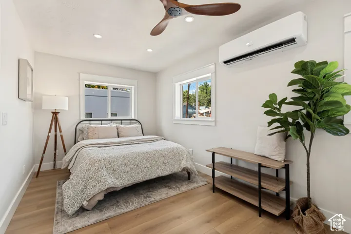 Bright bedroom with wood-finish flooring, metal bed frame, ample natural light from dual windows