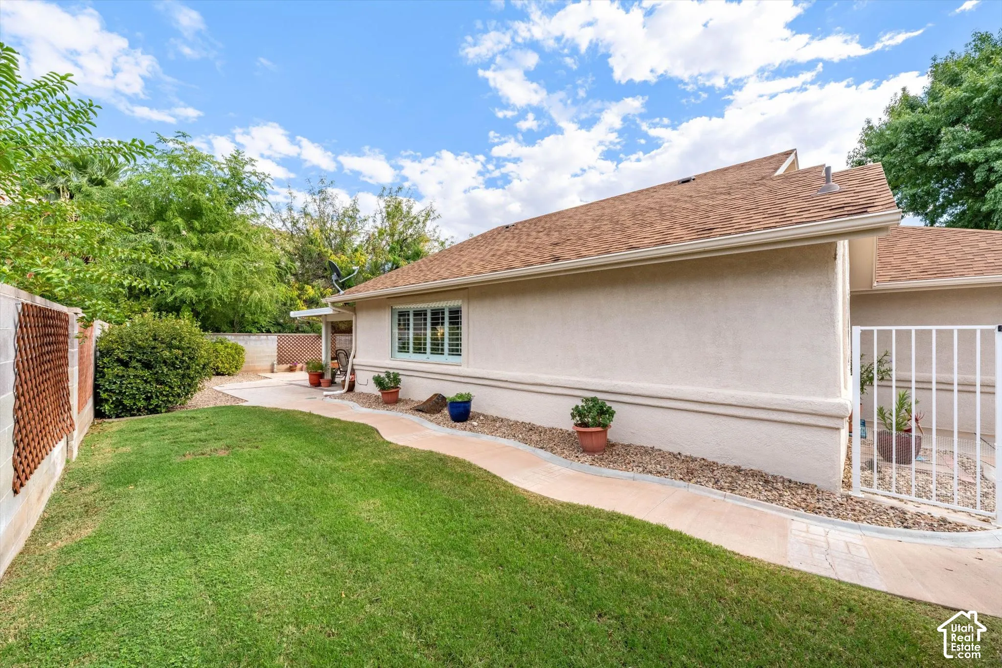 Manicured lawn with a curved concrete pathway and a stucco exterior