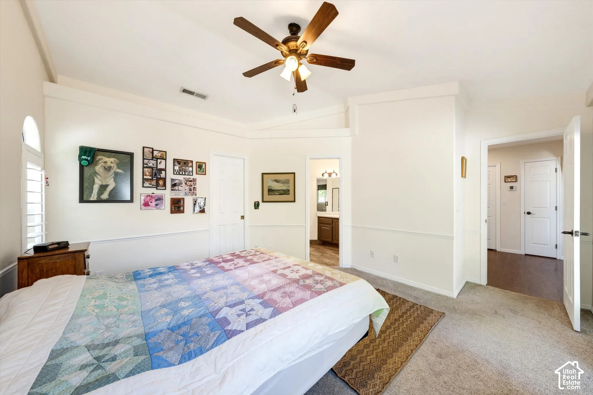 Vaulted ceiling with a ceiling fan, arched window with plantation shutters, wainscoting, and carpeted flooring