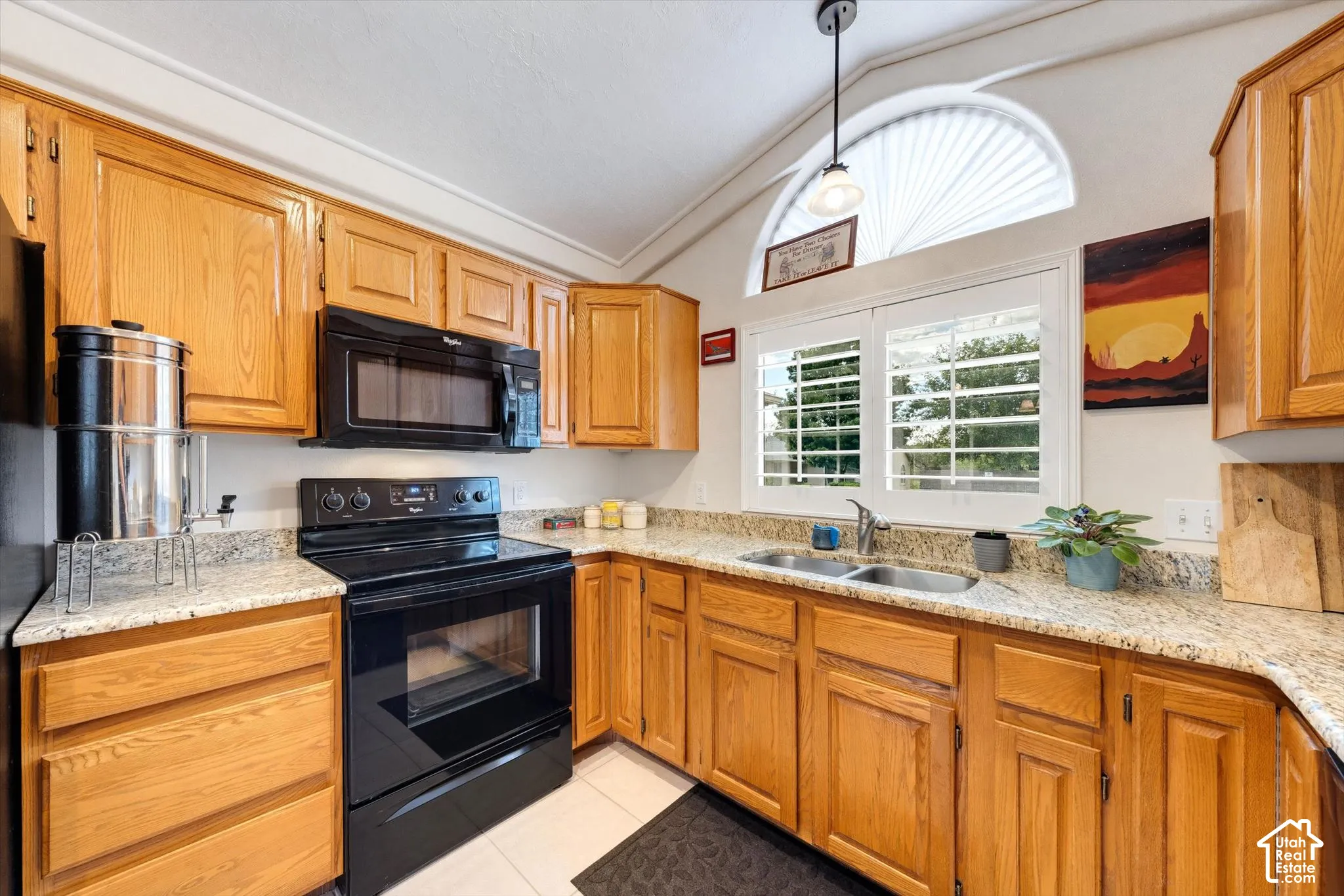 Kitchen featuring light wood cabinetry, granite-finish countertops, and black appliances
