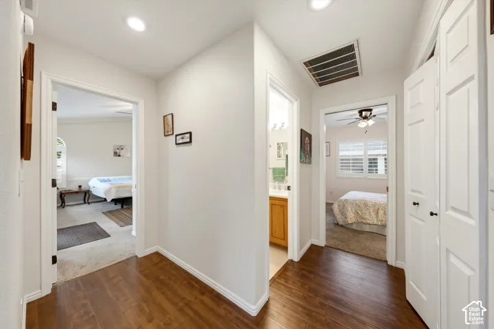 Wood-finish flooring throughout the hallway with recessed lighting and white paneled doors