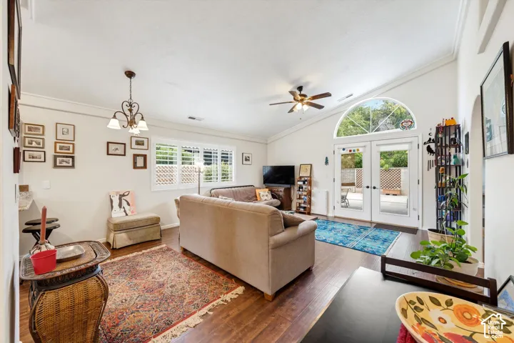 Vaulted ceiling with a ceiling fan, French doors with an arched transom, wood-finish flooring, and plantation shutters