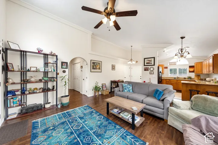 Vaulted ceilings with crown molding, wood-finish flooring, recessed lighting, arched doorway, and kitchen with breakfast bar