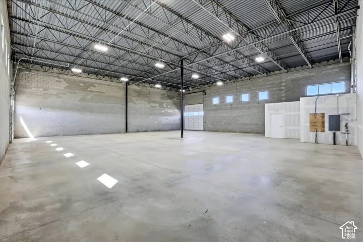 Expansive open-concept space featuring polished concrete flooring, exposed metal truss ceiling, and multiple overhead light fixtures