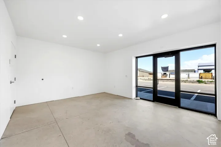 Concrete flooring, recessed ceiling lighting, white painted walls, and full-height exterior glass doors