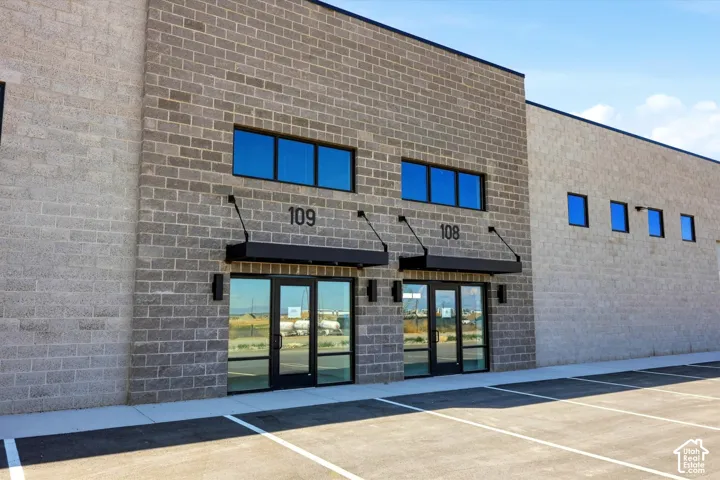 Modern brick commercial storefront featuring dual glass entry doors with transom windows, black awnings, and upper-level fenestration