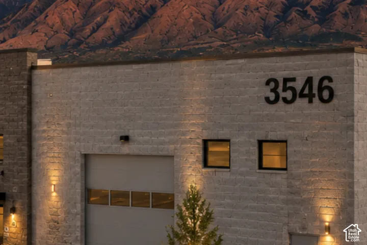 Stone block exterior with large address numbers, garage door, and modern sconce lighting