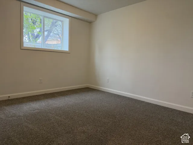 Neutral wall color, window with white trim, gray speckled carpeting, and white baseboards